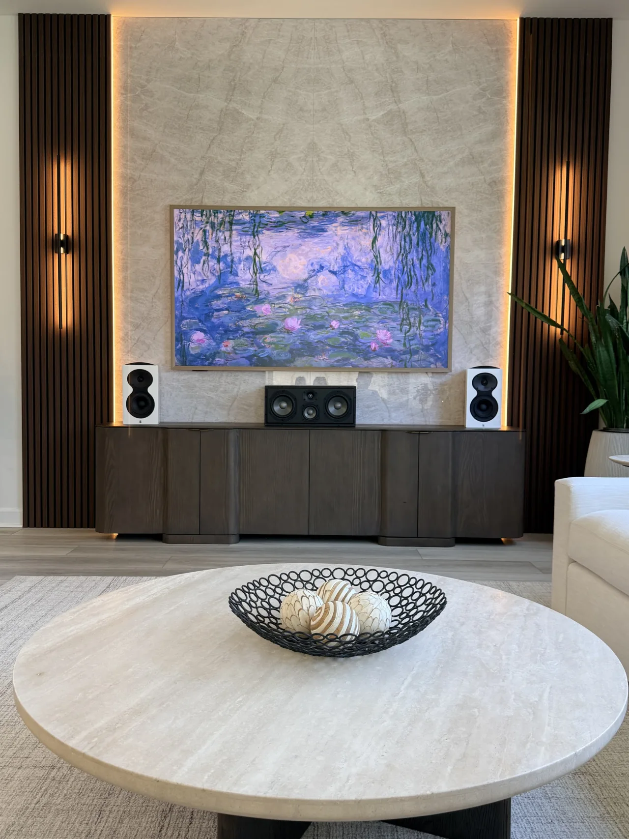 Real customer media wall combining Taj Mahal bookmatch panels with dark wood acoustic slat panels