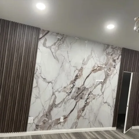 Real customer feature wall combining large-format PVC marble sheets with dark fluted panels
