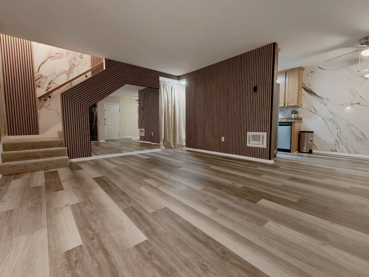 Customer living room and stairway finished with Gray Oak acoustic slat panels and marble-look wall panels