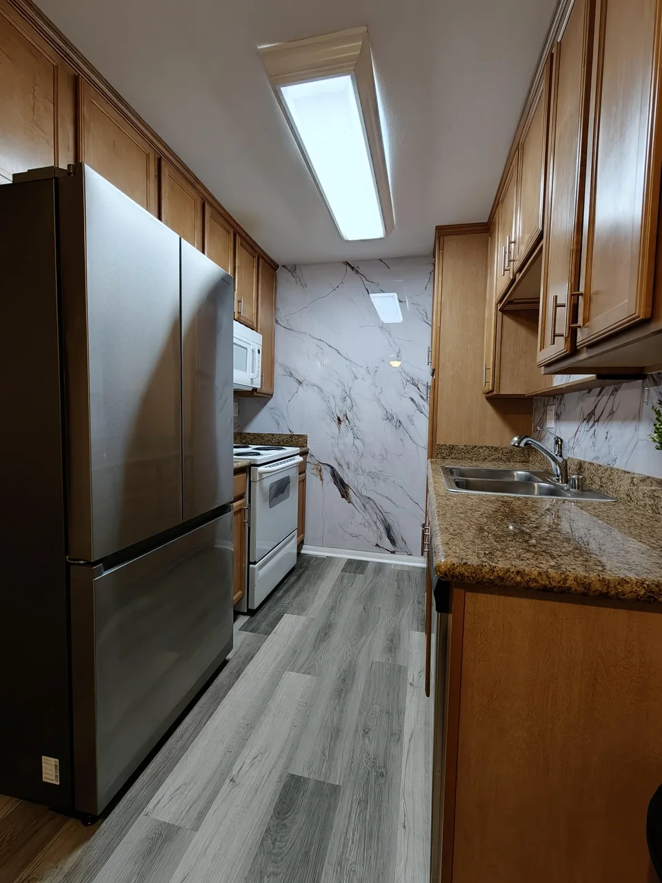 Customer galley kitchen with Fish Belly bookmatch marble panels on the end wall and backsplash