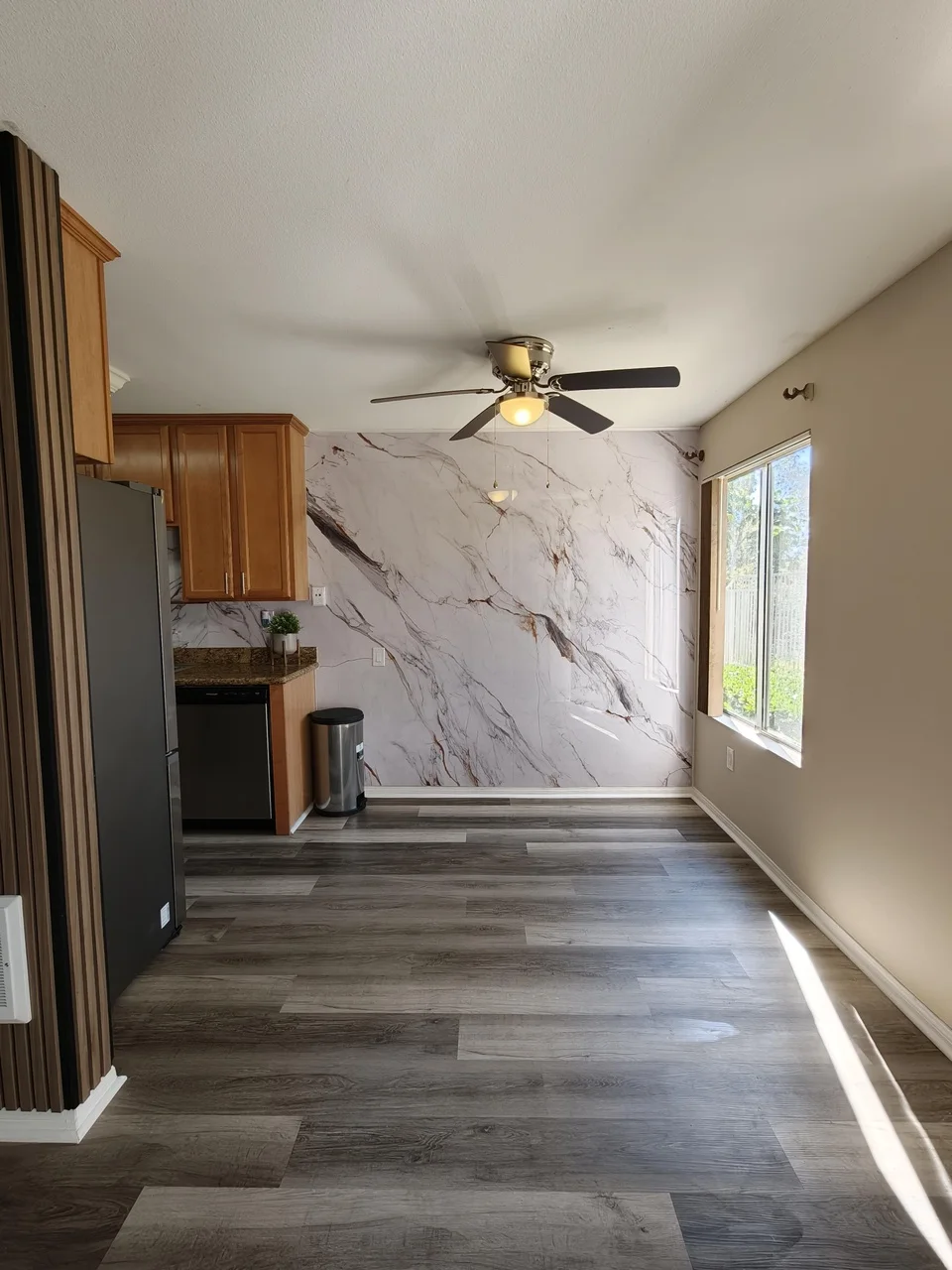 Wide view of a customer kitchen and dining area with a Fish Belly bookmatch marble panel feature wall
