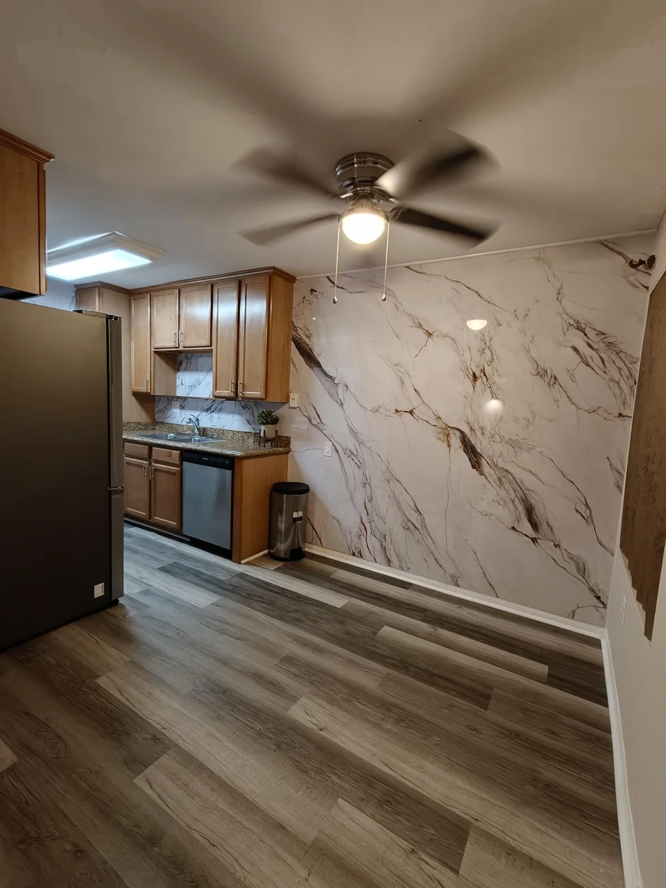 Angled view of a customer kitchen with Fish Belly bookmatch marble panels installed across the feature wall and backsplash