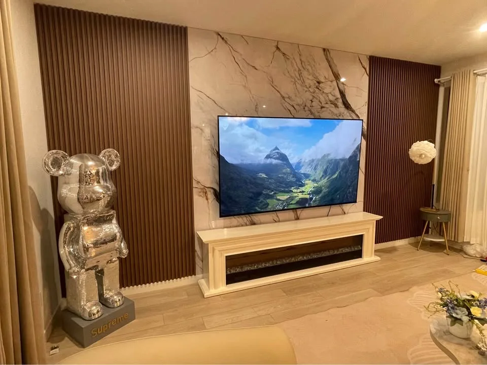 Customer living room TV and fireplace wall featuring Fish Belly bookmatch marble panels with fluted accent panels