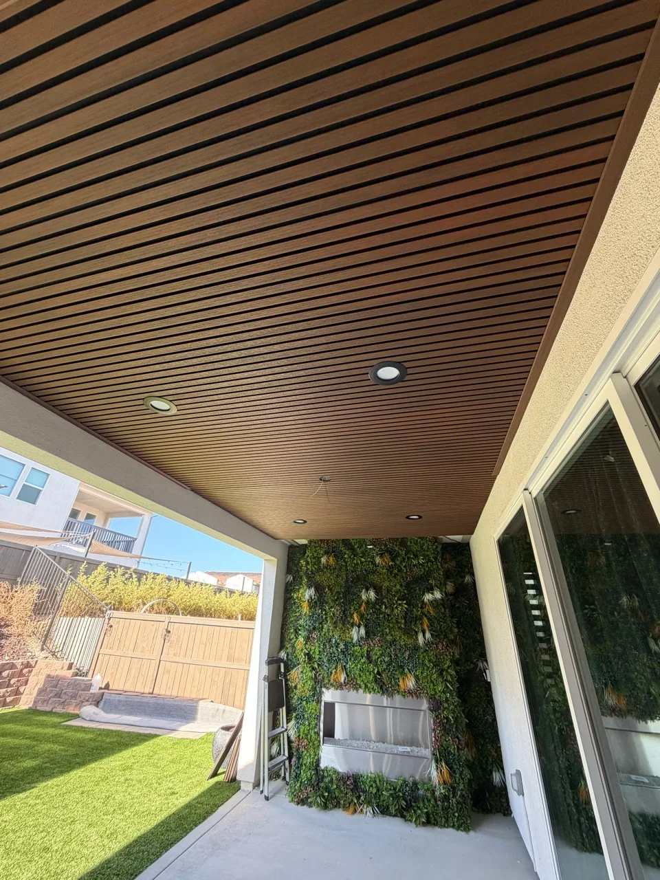 Customer covered patio ceiling finished with teak and black exterior composite slat panels